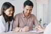 a man and a woman sitting at a table signing a document